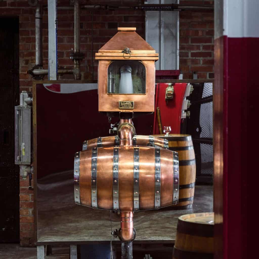 Polished copper casks with lantern top that is full of clear un-aged whiskey
