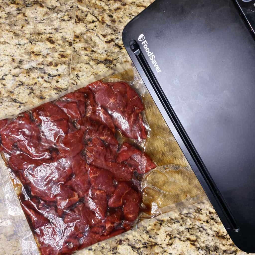 sliced steak marinating in vacuum sealed bag