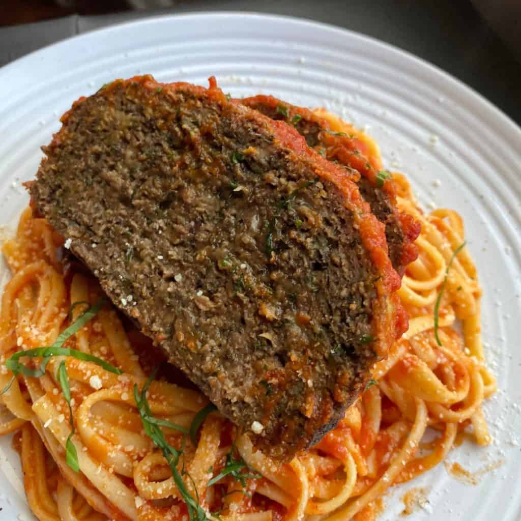 Meatloaf over a bed of spaghetti dressed with tomato sauce