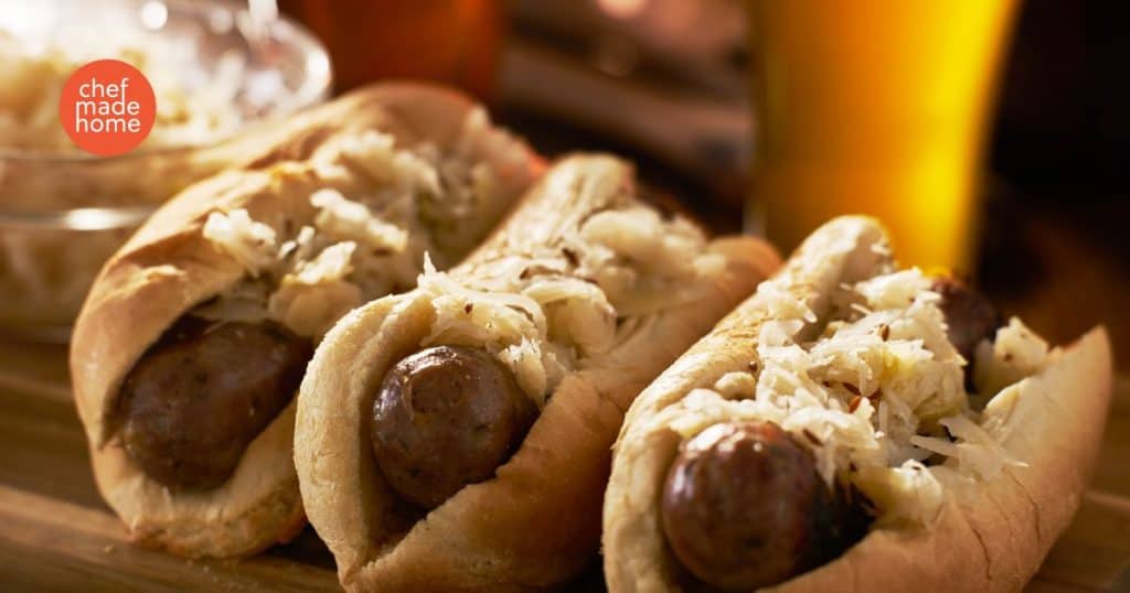 Brats and Kraut on a bun with a beer in the background