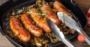 smoked brats on a bed of carmelized onions with a sprig of rosemary